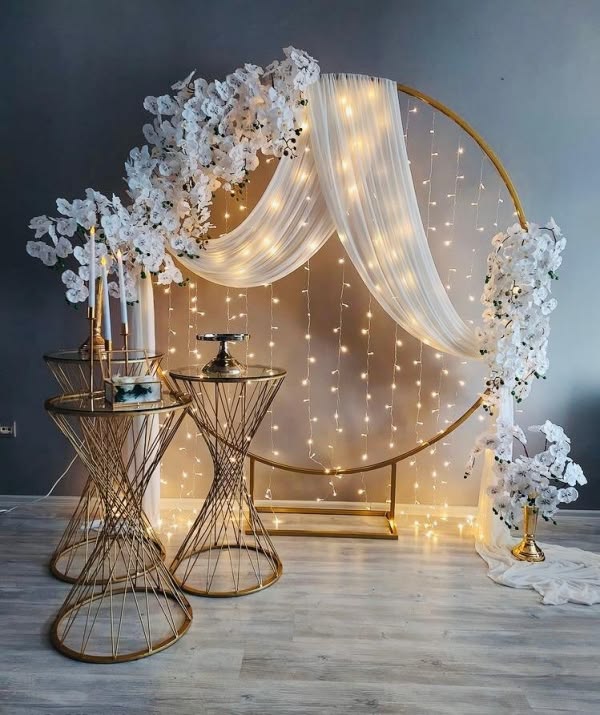 Cercle doré drapé de tulle blanc, rideau de lumières et guirlandes d'orchidées